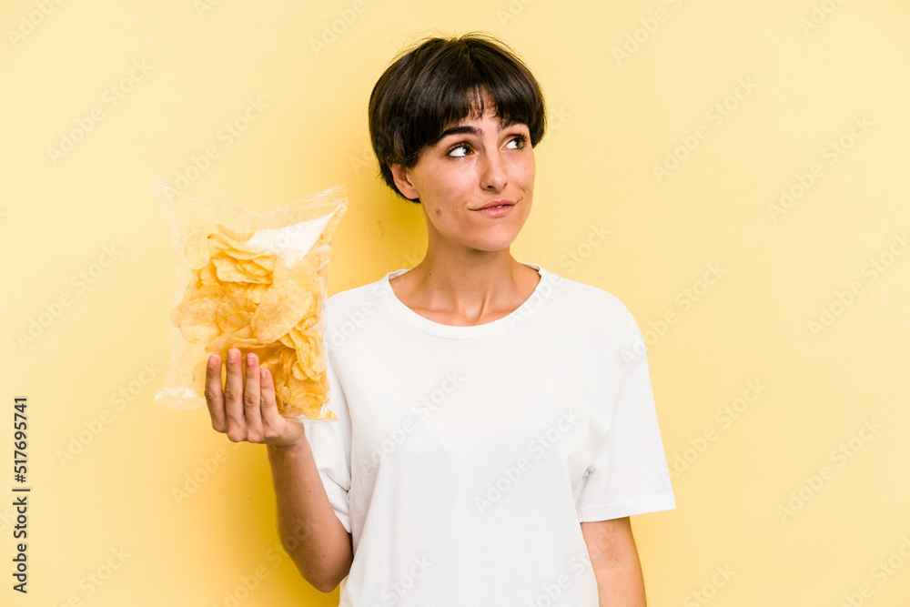Young caucasian man holding crisps isolated on yellow background dreaming of achieving goals and purposes Young caucasian man holding crisps isolated on yellow background dreaming of achieving goals and purposes