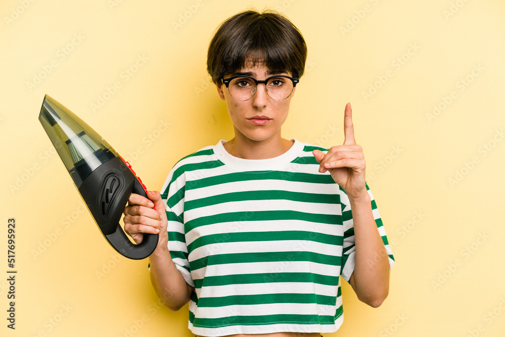 Young caucasian woman holding a hand vacuum cleaner isolated on yellow background having an idea, inspiration concept. Young caucasian woman holding a hand vacuum cleaner isolated on yellow background having an idea, inspiration concept.
