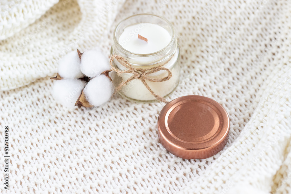 Soy wax candle with cotton flower on white cozy blanket. Soy wax candle with cotton flower on white cozy blanket.