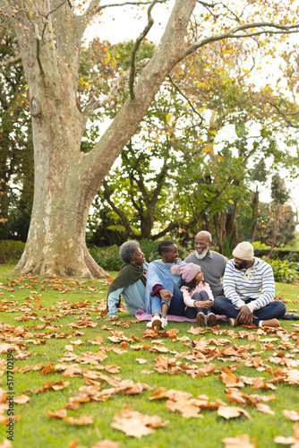 Vertical image of happy african american multi generation family in autumn garden