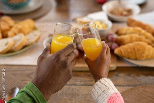 Image of hands of african american father and daughter toasting with juice