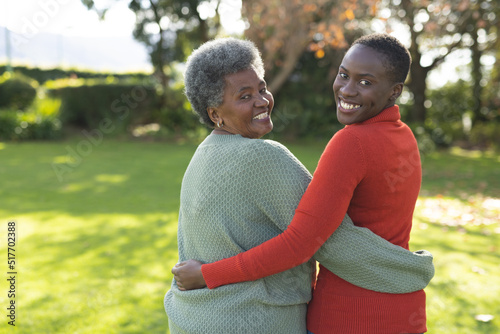Image of happy african american mother and adult daughter posing in garden