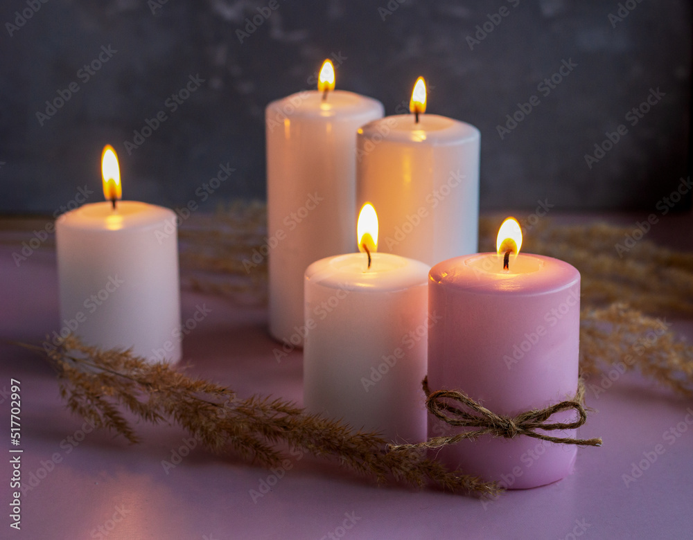 Set of white and pink wax candles with dried flowers in low lights Set of white and pink wax candles with dried flowers in low lights