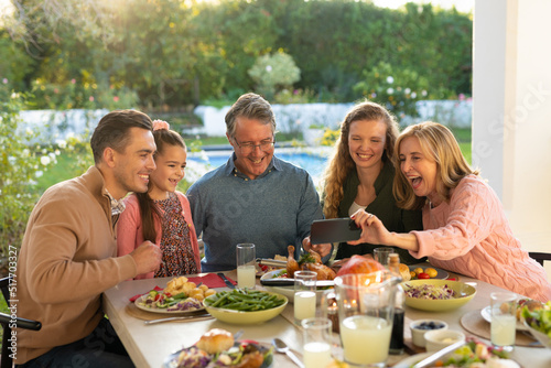 Image of multi generation caucasian family taking selfie after outdoor dinner