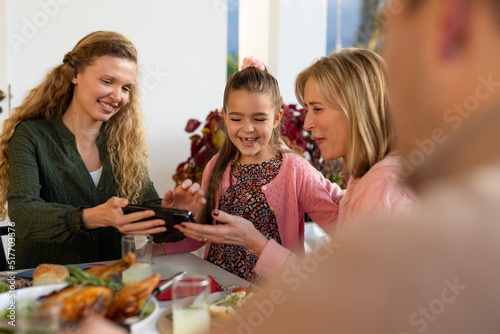 Image of multi generation caucasian family dining and using smartphone