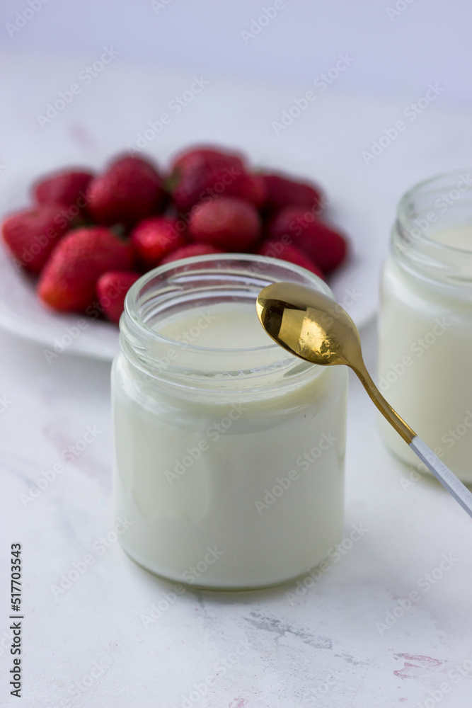 Homemade yogurt. Jars of yogurt and strawberries on a white table. Proper nutrition Homemade yogurt. Jars of yogurt and strawberries on a white table. Proper nutrition