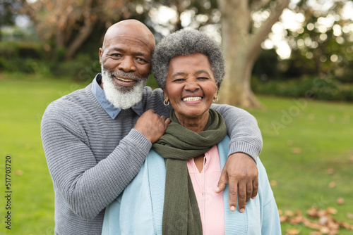 Image of happy african american senior couple posing at camera outdoors in autumn