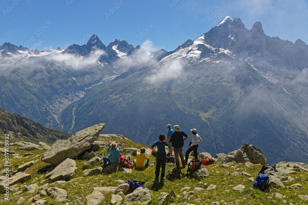 A group of hikers admires the mountains around Mont-Blanc. Mont-Blanc attracts travellers as the highest point in the Alps at 4810 meters, and it may be traversed in several ways.