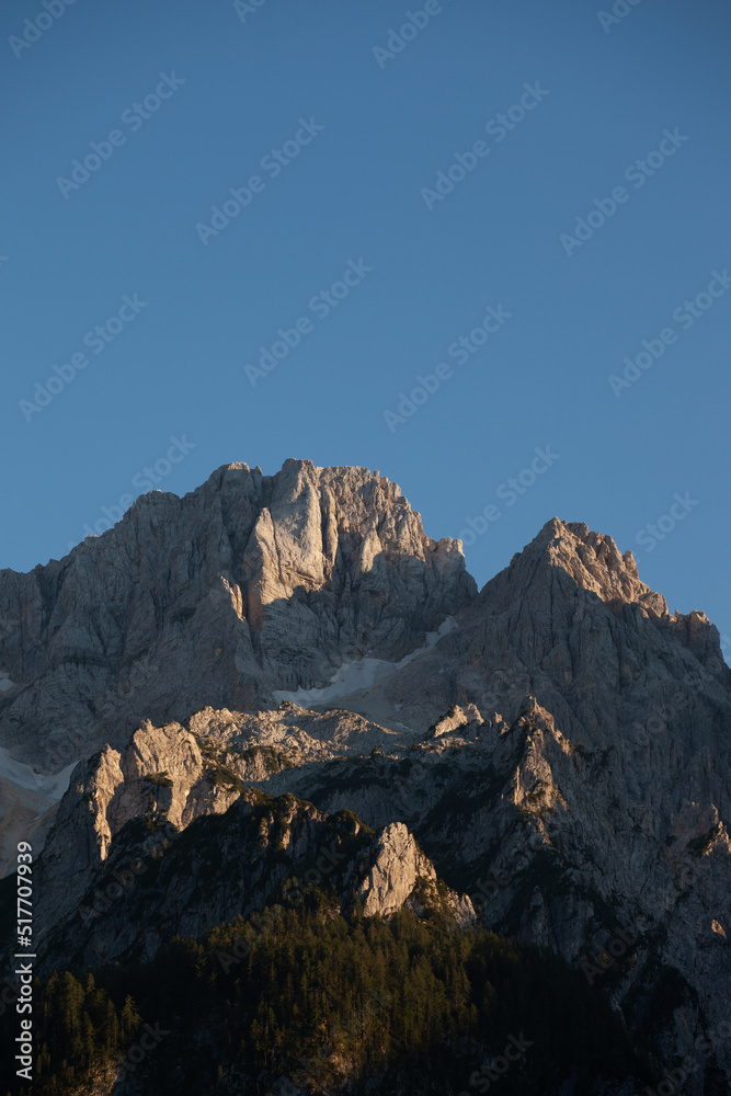 the top of the mountains, the forest and the blue sky. the rocky peaks in the Triglav national park in Slovenia with the blue sky and a softwood forest.