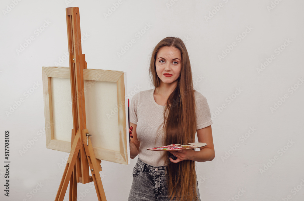 ?ute girl artist paints a picture on an easel with a brush and paints ?ute girl artist paints a picture on an easel with a brush and paints