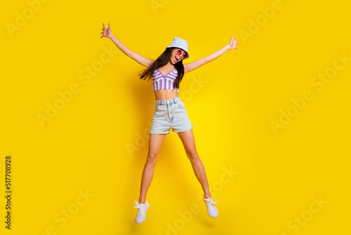 Full length photo of sweet charming girl dressed swimsuit bra cap jumping high like star isolated yellow color background