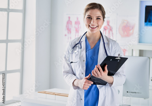 Smiling female doctor with a folder in uniform standing