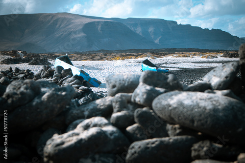 Blue vintage wooden boats on white beach of Caleta del Mojon Blanco. Sandy desert beach and rugged coastline. Orzola, Lanzarote, Canary Islands, Spain, Africa. photo