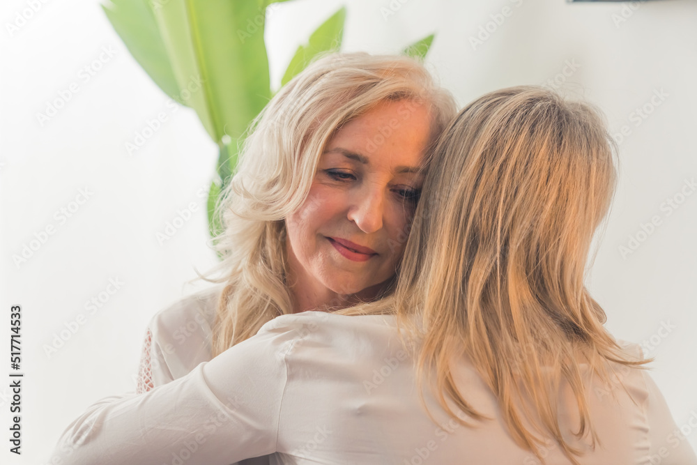 One unrecognizable caucasian woman with straight blonde hair hugging a middle-aged elegant lady with wavy hair. Support concept. High quality photo