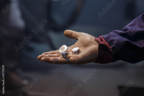 Man holds samples of silver metal.