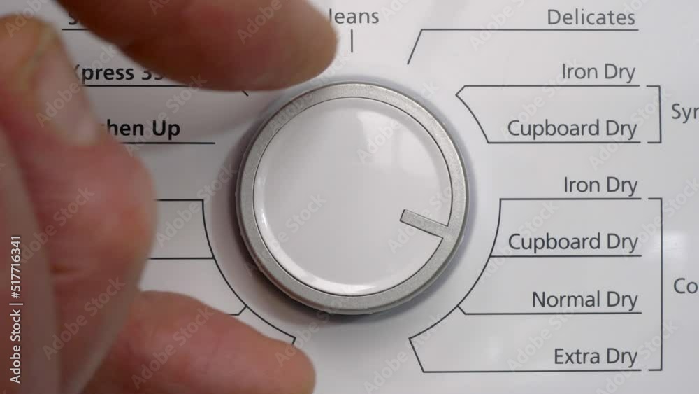 Closeup of a finger and thumb turning the dryness setting control knob / dial on a tumble dryer to normal dry.