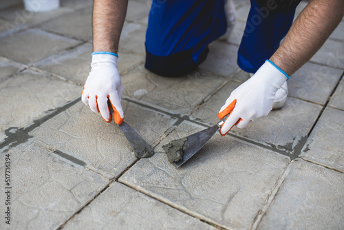 A man repairing the grout on a tile floor.