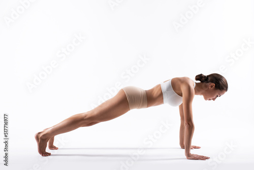 Beautiful fitness woman doing push-ups side view isolated on white.
