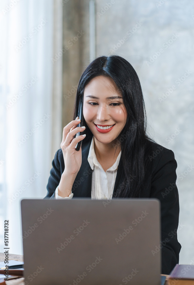 Young Asian lawyer woman professional in a suit sitting at a desk in her office. She looks, happy, hopeful and confident about her future. Young Asian lawyer woman professional in a suit sitting at a desk in her office. She looks, happy, hopeful and confident about her future.