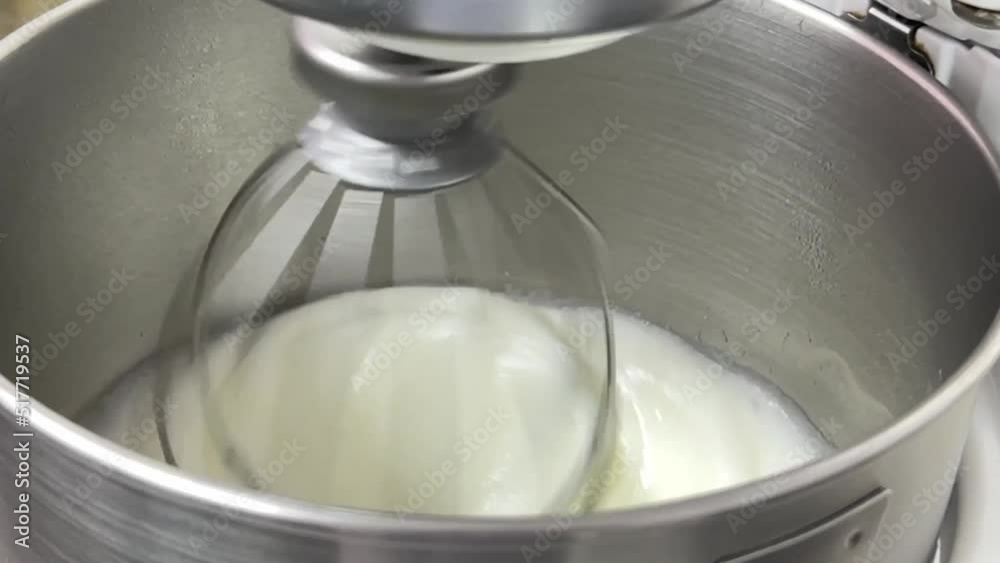 Slow motion delicious icing meringue buttercream mixing in the heavy duty mixer in the commercial bakery setting, close up shot. Slow motion delicious icing meringue buttercream mixing in the heavy duty mixer in the commercial bakery setting, close up shot.