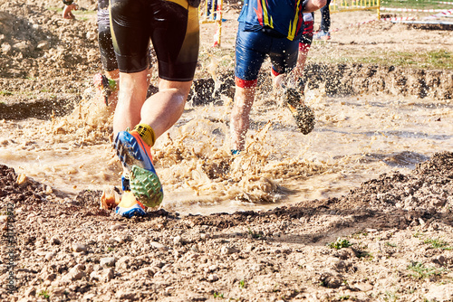 Group of participants in an obstacle course race running across a pool of water. Spartan race. Concept of effort