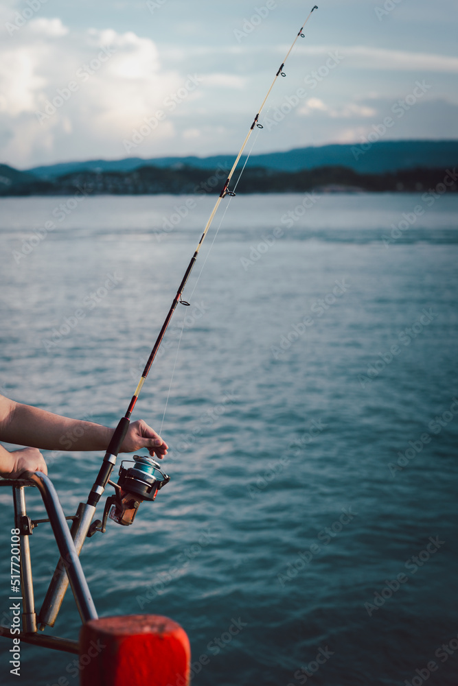 Fishing rod wheel closeup, man fishing from the boat in the sea Fishing rod wheel closeup, man fishing from the boat in the sea