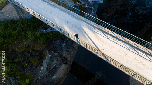 Landscape photographer with camera on the bridge over the river. Drone view from above