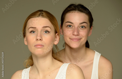 beauty portrait of two young attractive blonde and brunette girls on a light background isolated