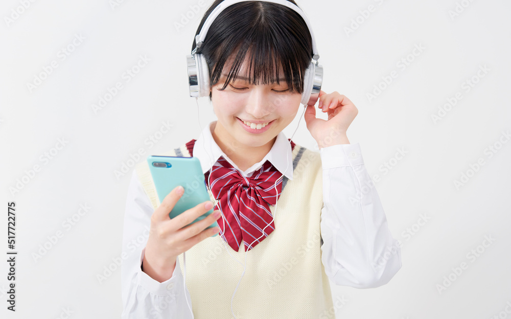 ヘッドフォンで音楽を聴く女子高生 白背景 ヘッドフォンで音楽を聴く女子高生 白背景