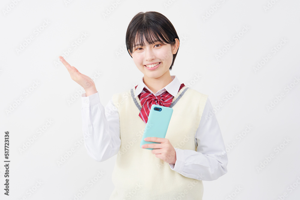 スマホを持って掌で左側を指す女子高生 白背景 スマホを持って掌で左側を指す女子高生 白背景