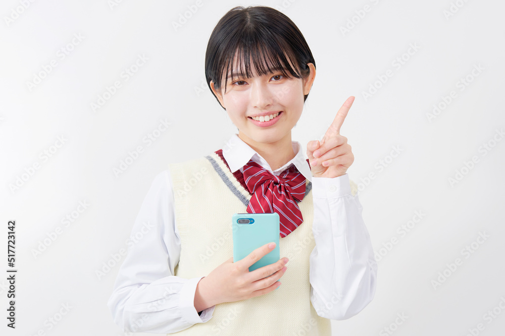 スマホを持って右側を指差す女子高生 白背景 スマホを持って右側を指差す女子高生 白背景