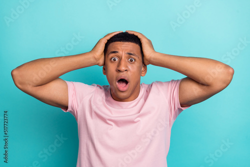 Photo of funky impressed young man dressed pink t-shirt arms head open mouth isolated turquoise color background