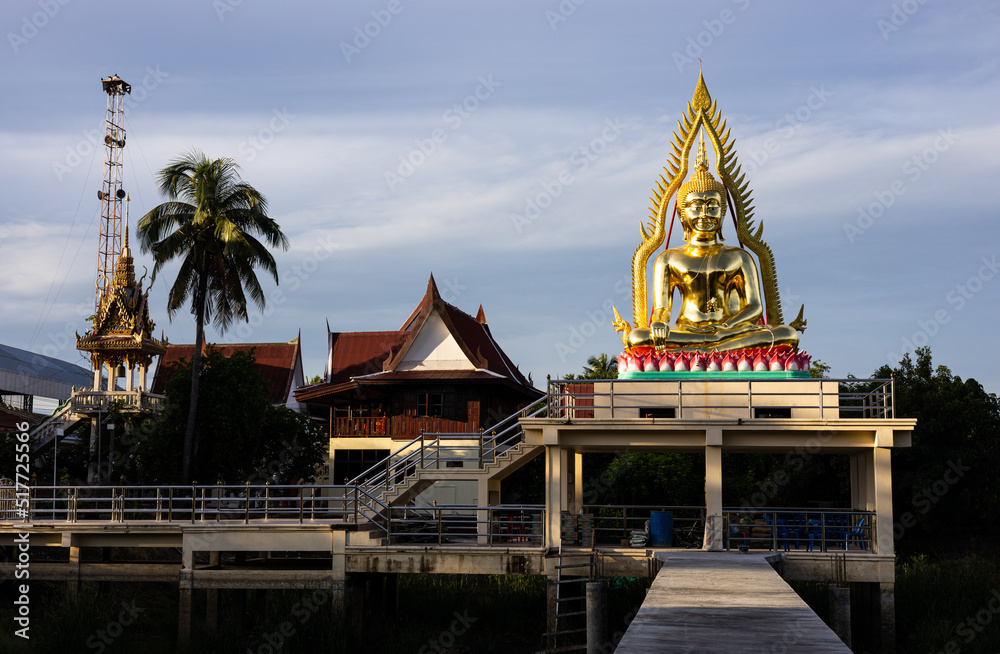 Fototapeta premium A view of a large meditating golden Buddha statue enshrined on a concrete hall structure.