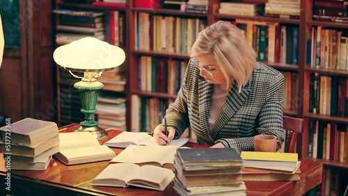 Woman professional historian working with archives late at night, taking notes photo