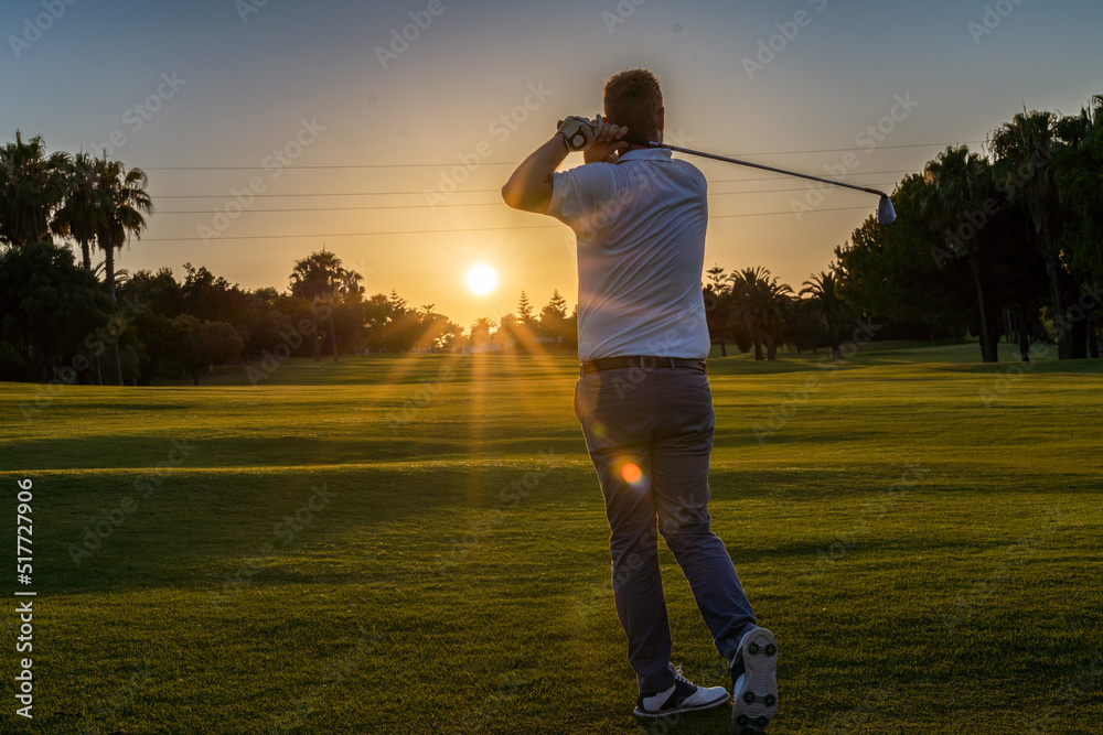 Good strike, professional golfer looking trajectory of the ball, golfer hitting golf ball standing on course at sunny evening Good strike, professional golfer looking trajectory of the ball, golfer hitting golf ball standing on course at sunny evening