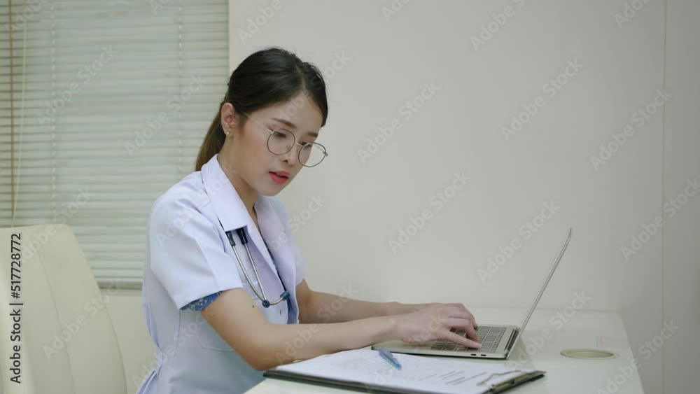 Asian female doctor working on papers at desk in room
Asian female doctor working on papers at desk in room