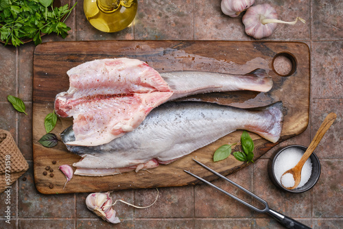 Delicious fresh fish on a kitchen board on a dark vintage background. Fish with aromatic herbs and spices. The concept of healthy eating and cooking.