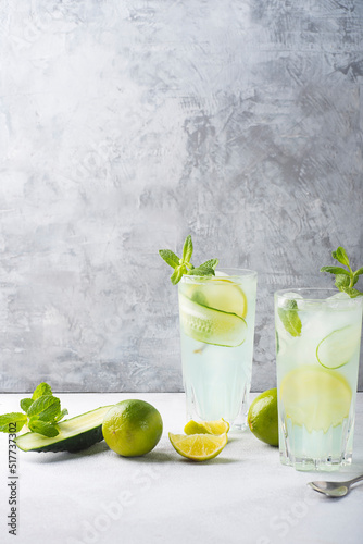 Detox summer cocktail with mint, cucumber and lime or mojito cocktail in highball glasses on a gray concrete stone surface background. Fresh drinks. Copy space