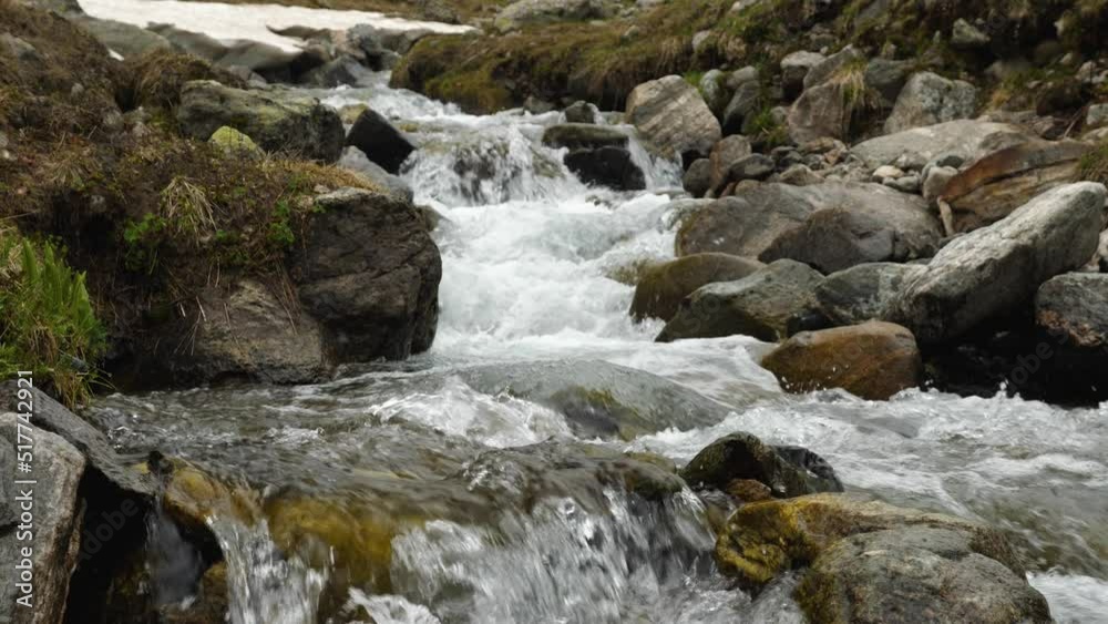 Close-up of a clear stream running over rocky boulders in the mountains. Melt water runs down the stone bed in rapids. Wildlife. Background video Close-up of a clear stream running over rocky boulders in the mountains. Melt water runs down the stone bed in rapids. Wildlife. Background video