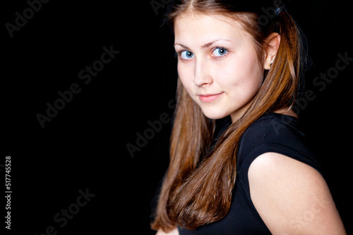 Cute girl - brunette looks at the camera. Black background