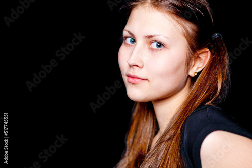 Cute girl - brunette looks at the camera. Black background