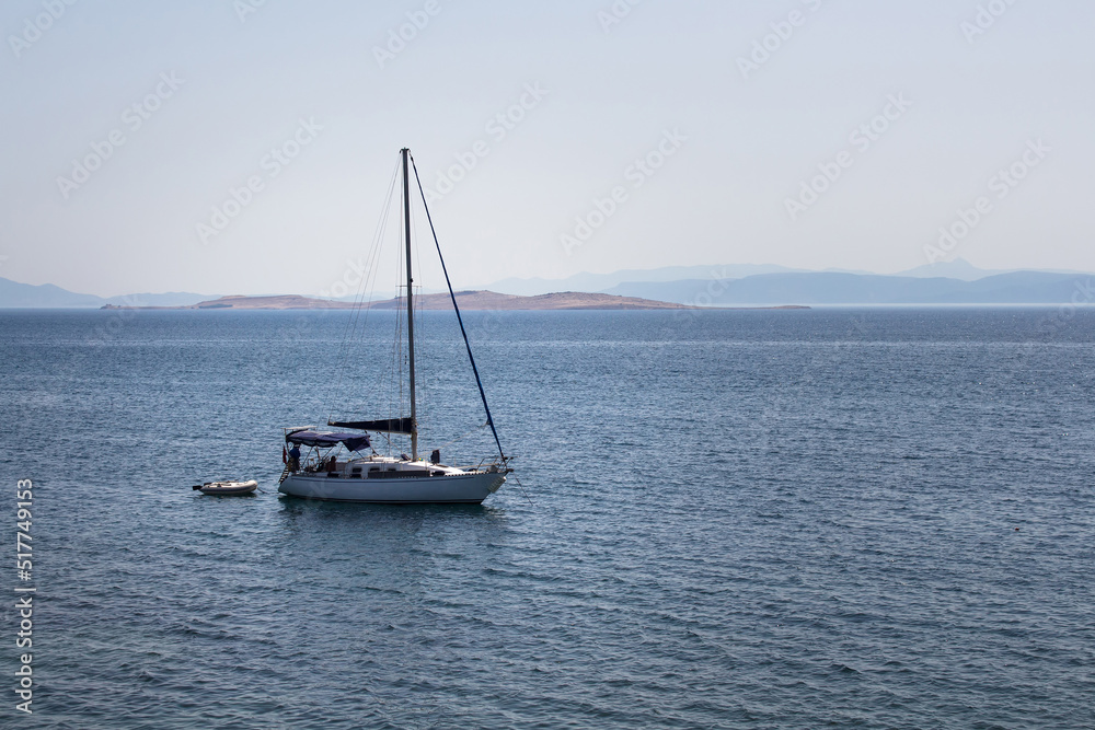 View of a sail boat, Aegean sea and landscape captured in Ayvalik area of Turkey. It is a sunny summer day.