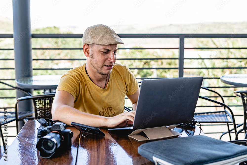 Horizontal image of a Hispanic man sitting at his computer in a restaurant teleworking.