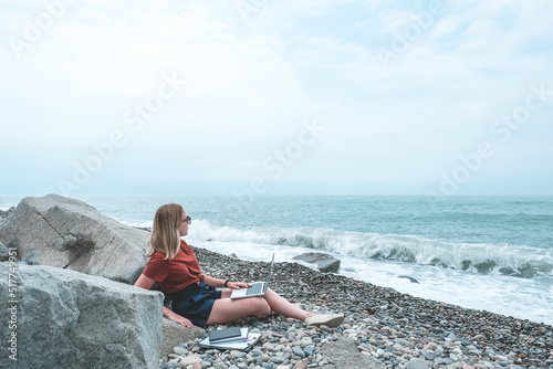 Remote work.Girl freelancer works remotely on the seashore.workation, remote work,WFVH,Van Life vibes work from vacation home,work travel,remotely work.Travelling