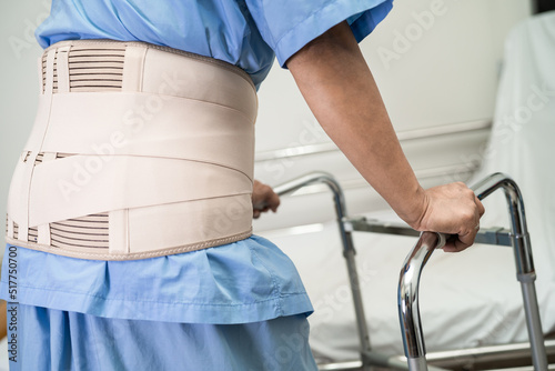 Asian lady patient wearing back pain support belt for orthopedic lumbar with walker.