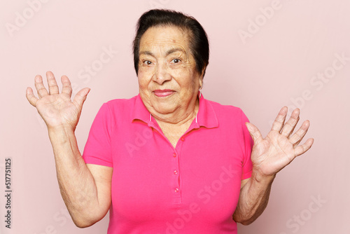 Funny Latin or Hispanic senior woman making a "I don't know" pose against pink background