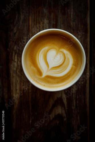 A cup of cappuccino with a heart latte art. Vintage wooden background, top view.