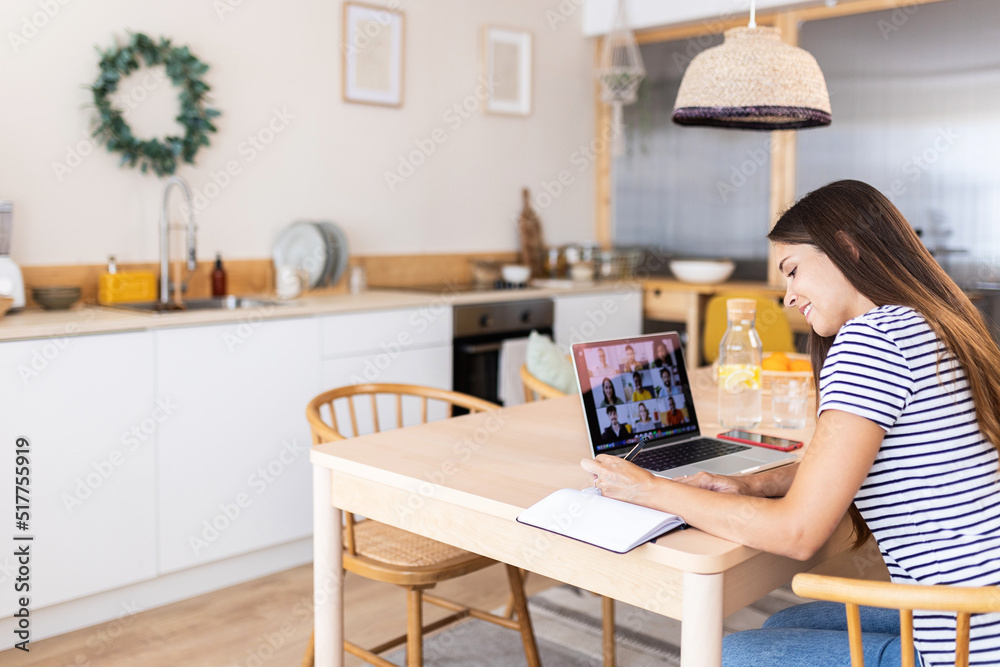Young adult woman using laptop computer while having a video call with multiracial team employees working from home office - Virtual meeting conference concept