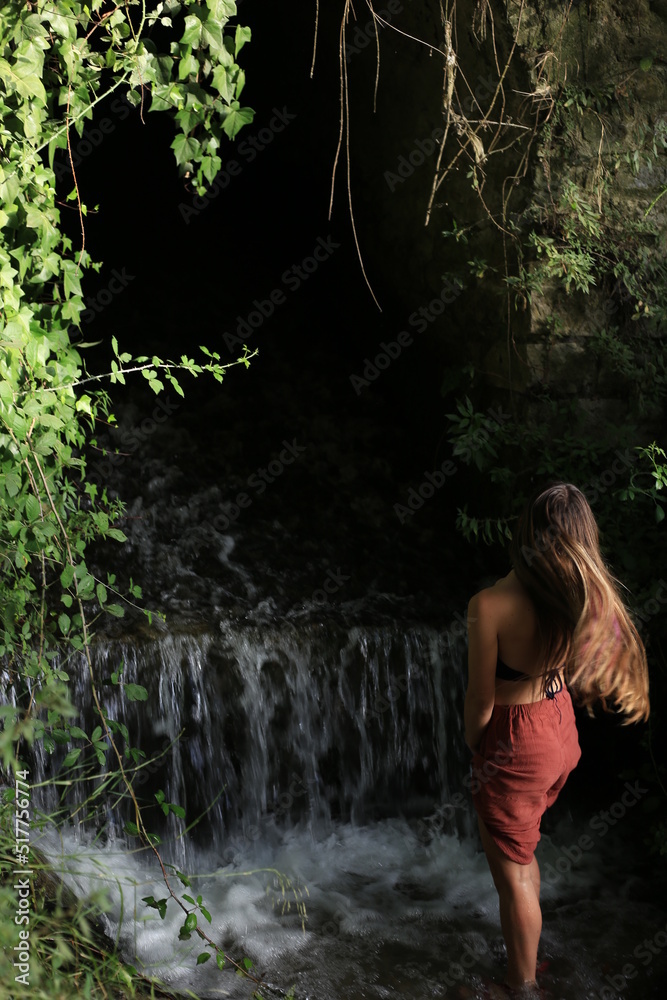 blonde young girl moves her hair in nature next to a small waterfall blonde young girl moves her hair in nature next to a small waterfall