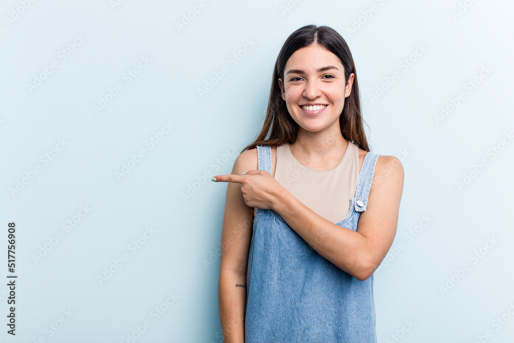 Young caucasian woman isolated on blue background smiling and pointing aside, showing something at blank space. Young caucasian woman isolated on blue background smiling and pointing aside, showing something at blank space.